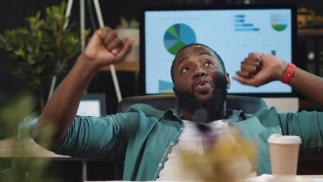 Closeup-satisfied-african-american-businessman-dancing-in-night-office