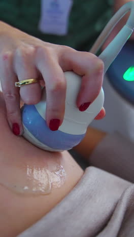 hand of a doctor holding ultrasonic device moves by the big pregnant belly of a patient. close up. ultrasound check up concept. vertical video