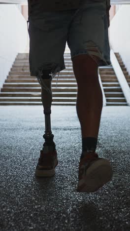 man with prosthetic leg walking down stairs in a tunnel