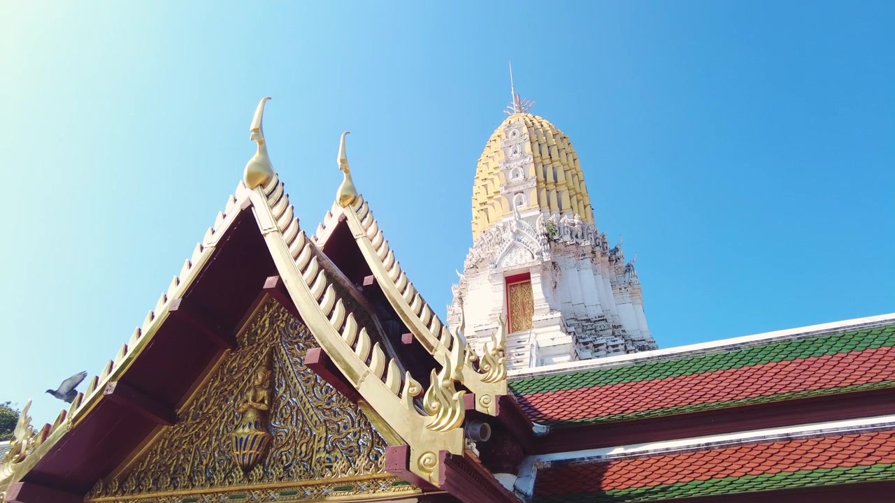タイのワット・プラシーラッタナーマハータートにある、黄金の装飾が施された寺院の屋根と古代のプラーン塔