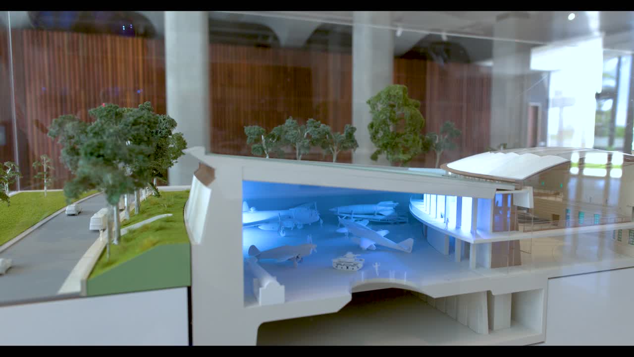 Un modello architettonico in miniatura dettagliato mostra una sezione trasversale di un museo con illuminazione interna blu.