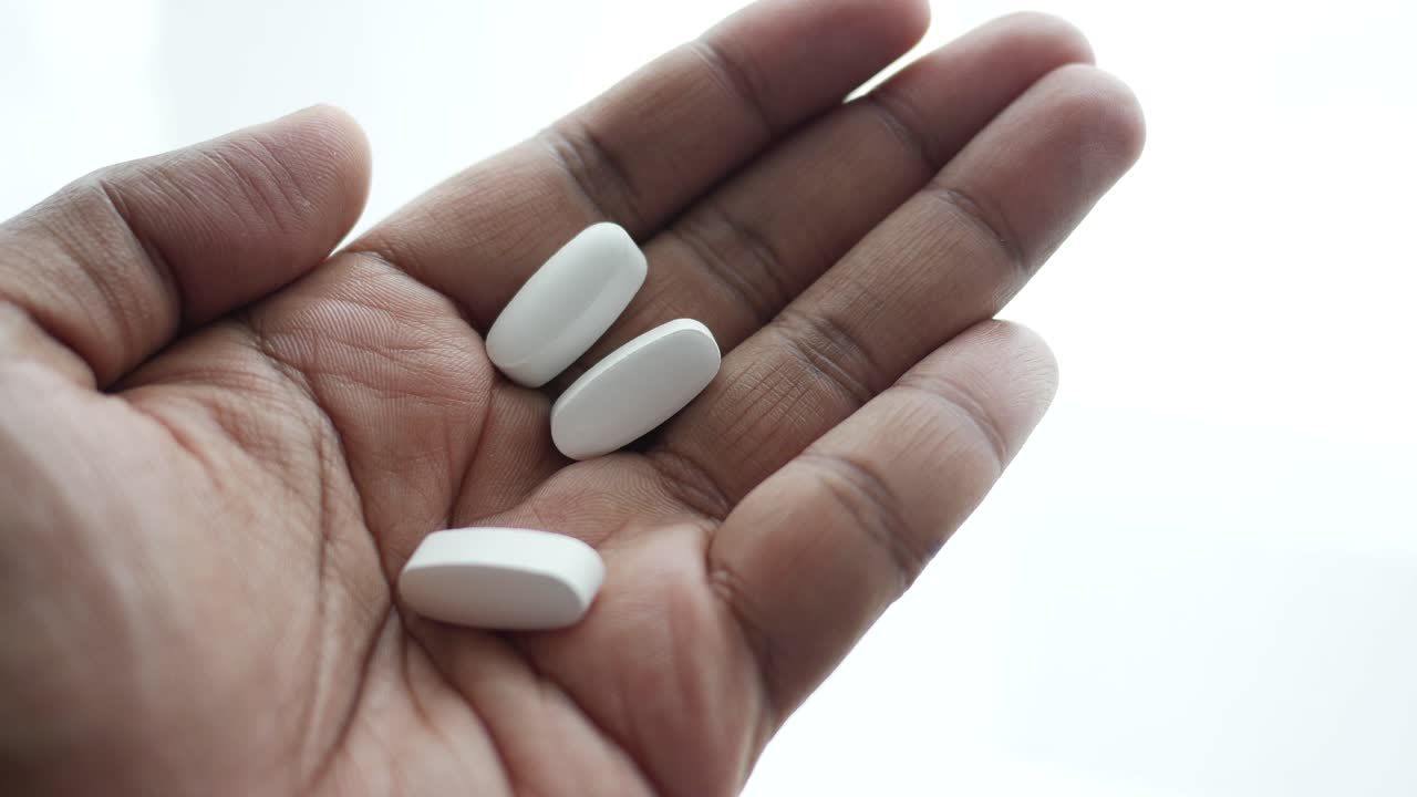 la mano sosteniendo pastillas blancas