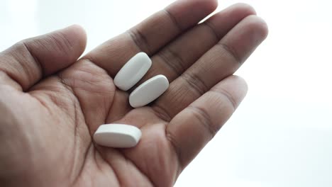 la mano sosteniendo pastillas blancas