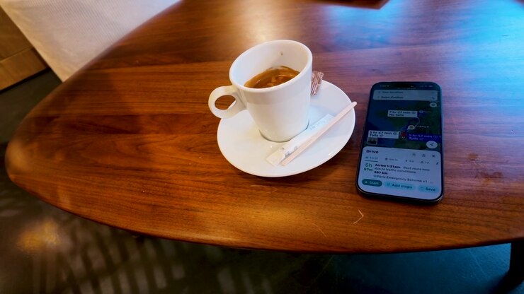 A high-angle shot pans across a wooden table holding espresso and a smartphone navigation app