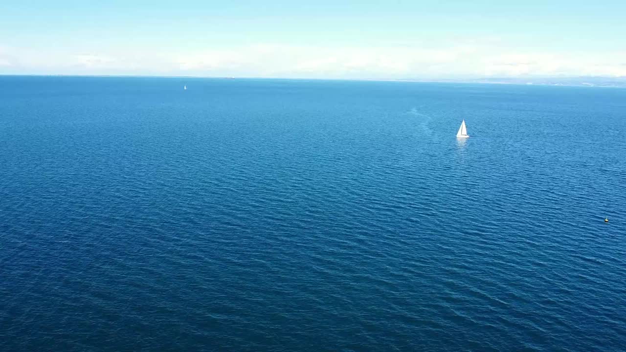 empuje aéreo de la costa al mar con velero en el fondo en el mar azul