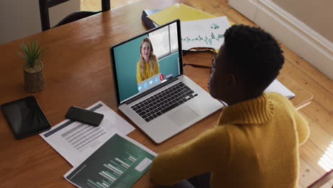 mujer afroamericana que usa una computadora portátil en una videollamada con una colega que trabaja desde casa