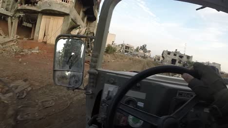 soldado israelí conduciendo un humvee por una carretera a través de las calles destruidas de gaza