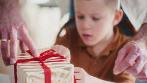 little boy helps his dad wrap a christmas present