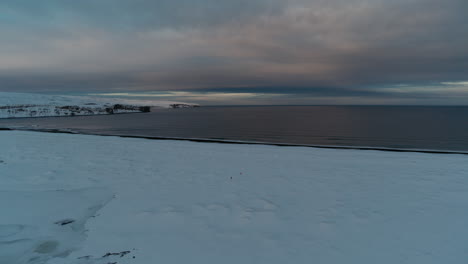walking through the snow to get to the coastline in iceland during winter shot with a drone