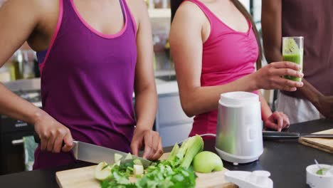 group of diverse young people making and drinking green healthy smoothie together at home