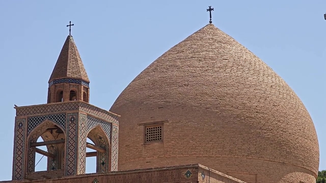 Antica chiesa in mattoni con cupola e campanile contro un cielo azzurro limpido