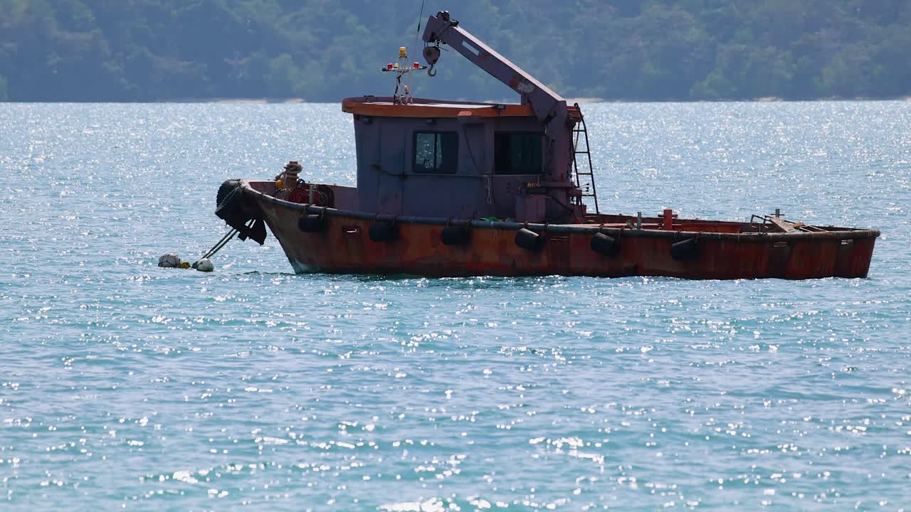 A tug boat moves steadily across the ocean near Phuket, Thailand, under bright daylight, showcasing serene maritime activity