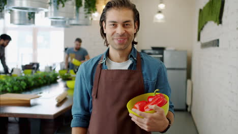 man holding red bell peppers in a kitchen