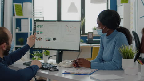 invalid manager with face mask explaning to black employee financial evolution