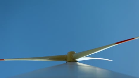 dynamic close-up of a spinning wind turbine blade against a clear blue sky