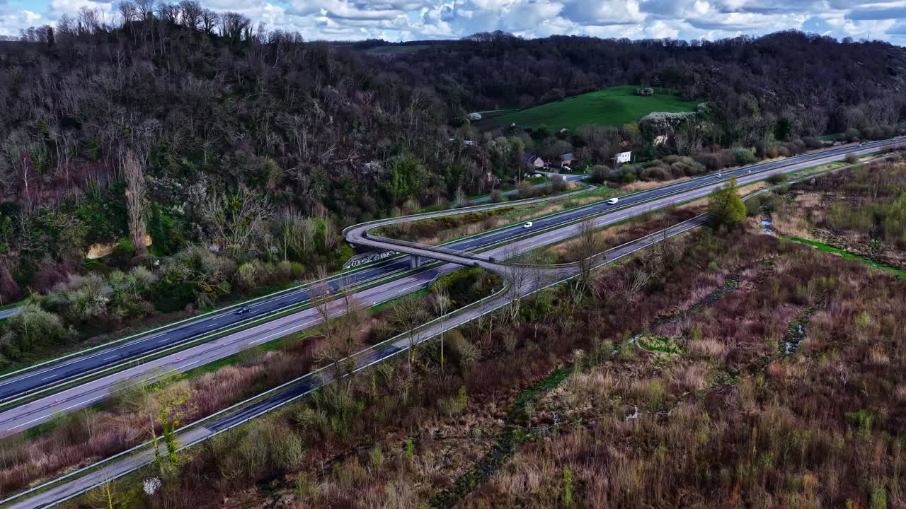 Le Havre, France - Winding Roads Cut Through Lush Hills and Forests Under a Partly Cloudy Sky - Aerial Drone Shot