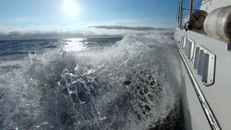 slow motion side view of boat's wake as it sails in open ocean at sunset