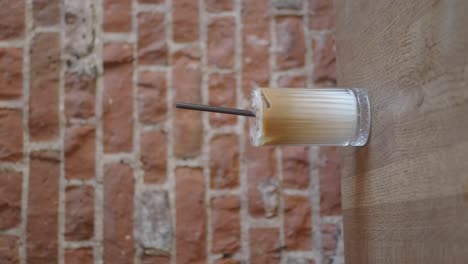 hand reaching for an iced coffee in a cafe