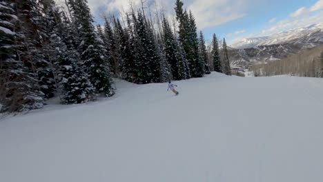 Woman-snowboarder-performing-a-Ollie-and-continue-down-slope,-Aspen-,-Colorado