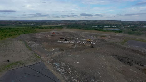 Dump trucks tip tons of trash into a landfill site, drone aerial video.