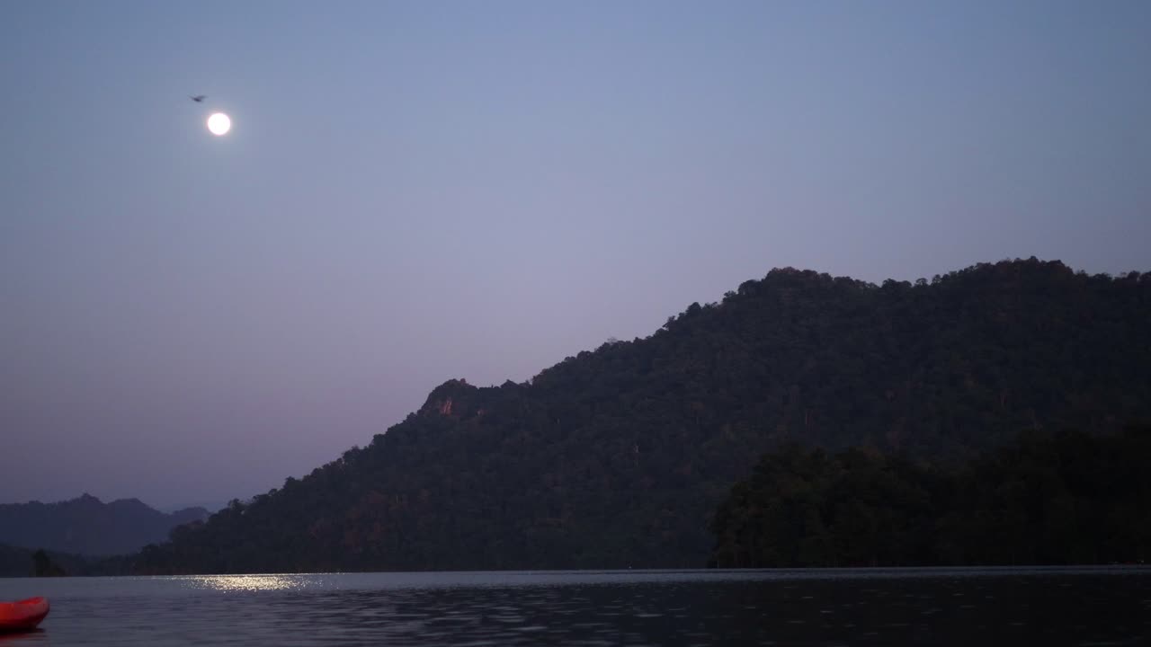 Rekaman selang waktu bulan terbit di atas danau gunung yang tenang