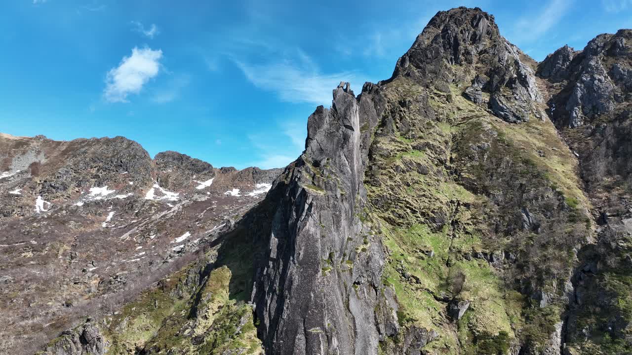 Iconic Svolvaergeita rises sharply with Floya and bright sky as drone tilts upward