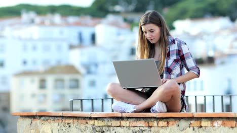 serious teen writing on a laptop on vacation