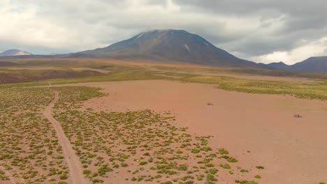Aerial-cinematic-shot-following-a-dirt-road-showing-a-volcano