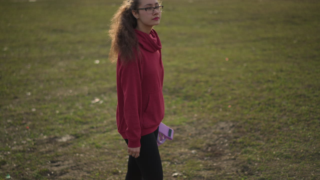 Teen In Field, Adolescent Captures Thoughtful Moment Amidst Natural Meadow Surroundings, Teenager Wearing Hoodie And Glasses Pauses Quietly In Expansive Grassy Plain During Late Afternoon