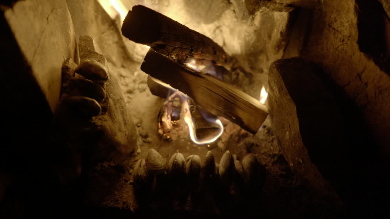 야생 마초 홍합의 느린 패닝 샷이 오래된 벽난로의 열린 장작불 앞에서 천천히 요리합니다.