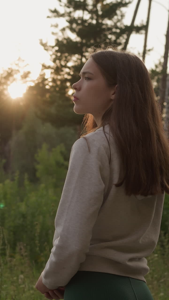 una mujer solitaria se encuentra en medio del bosque. una mujer triste piensa en el significado de la existencia caminando en un entorno salvaje al atardecer por la noche. devastación y depresión.