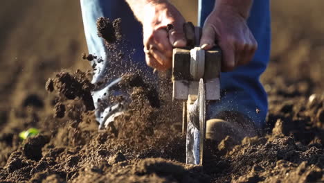 person working the soil with a gardening tool