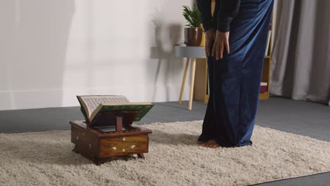 close up of muslim woman at home sitting and reciting from the quran