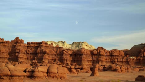 gorgeous stunning tilt up shot of the beautiful goblin valley utah state park mushroom rock formations with red and white rock mountains in the background on a warm sunny summer day