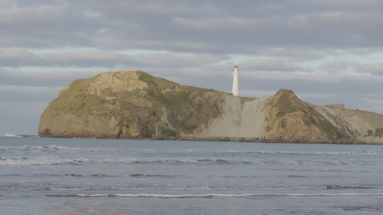 Wide shot of New Zealand's rock formation and lighthouse at Castle Point Beach