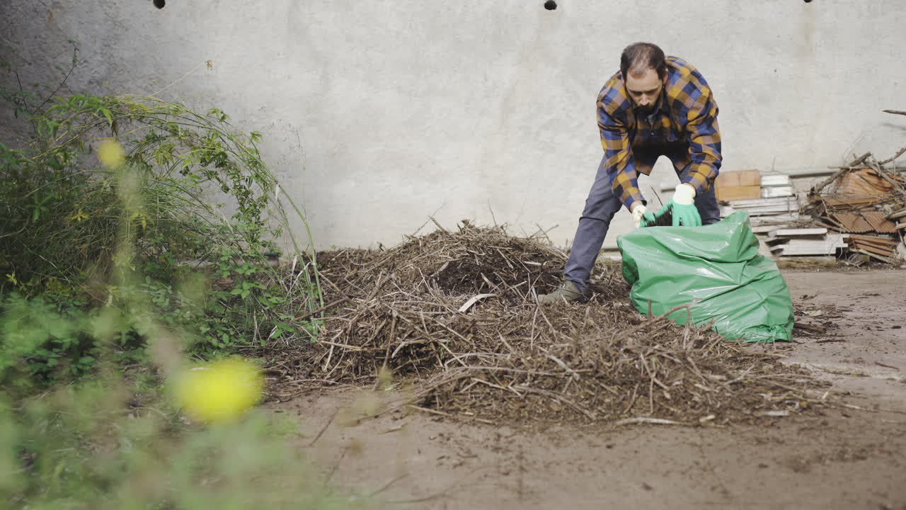 caucasian male working on his garden filling a bag with trash waste from the gardening job