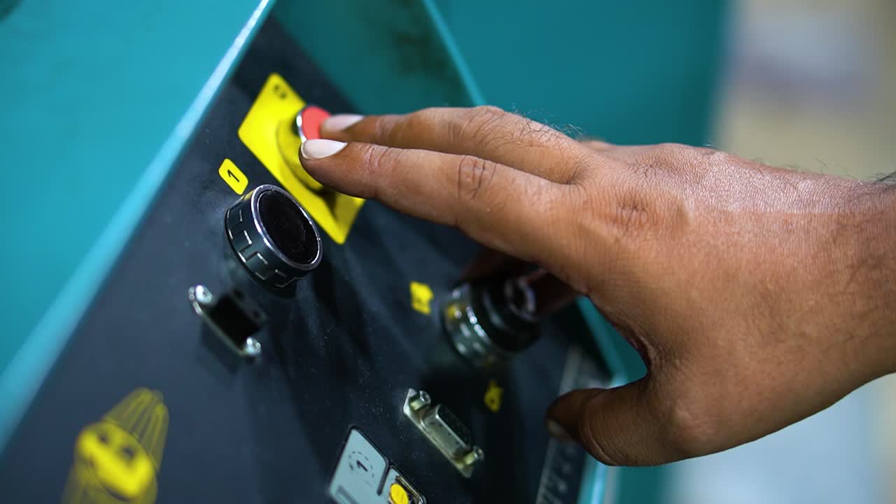 A man's fingers pressing the button of a machine panel to make it work - the start stop button on the machine