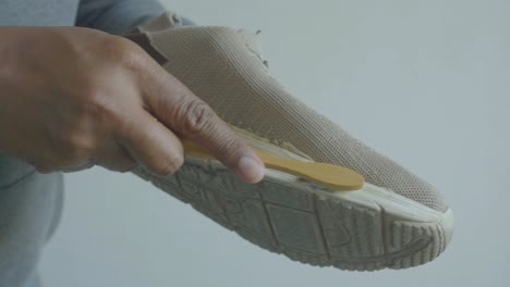 man cleaning his sneakers with a wooden brush