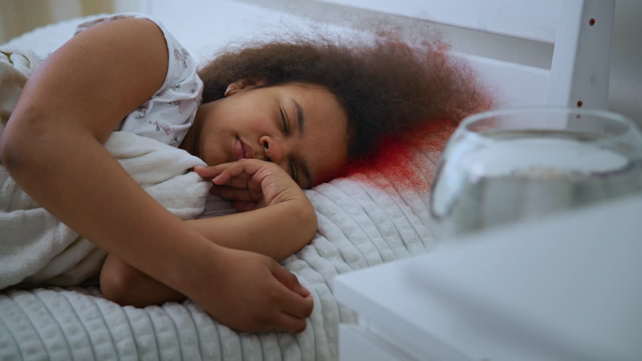 Peaceful young girl sleeping soundly in bed, unconscious of growing red blood stain gradually spreading across pillow from her hair
