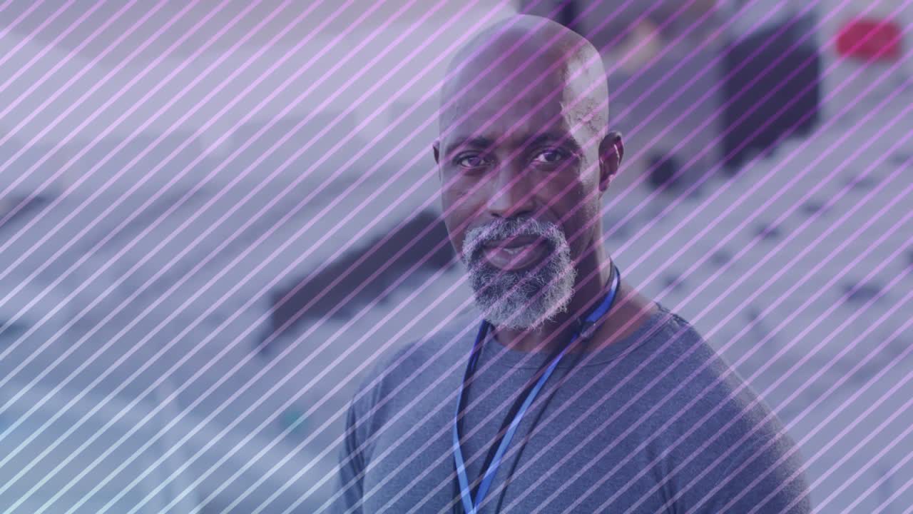 Senior man lifting head smiling in health lobby, zooming revealing purple overlay and blue lanyard