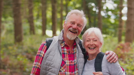 Portrait-Of-Loving-Retired-Senior-Couple-Walking-In-Woodland-Countryside-Together