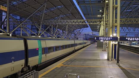 descending along escalator to empty concrete platform at dusk with ktx train waiting, doors closed with no people around