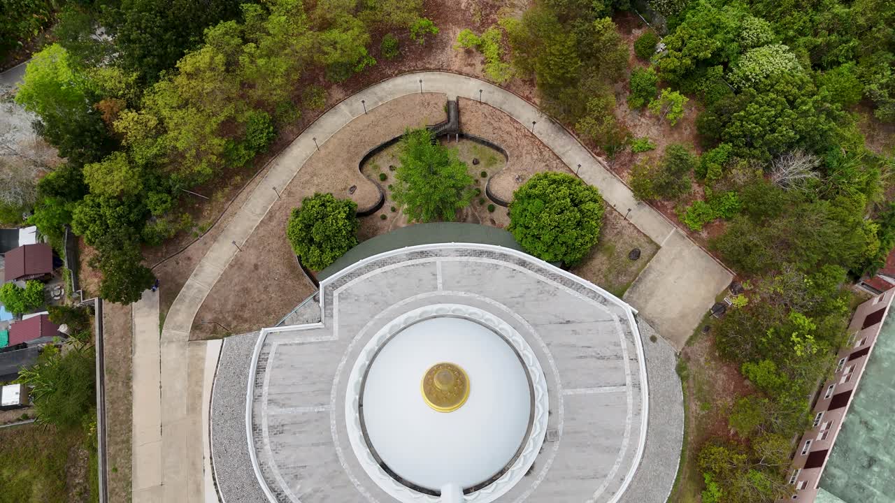 las imágenes de drones capturan una serena vista aérea de un templo budista en phuket, tailandia, que muestra su arquitectura circular y sus exuberantes alrededores.