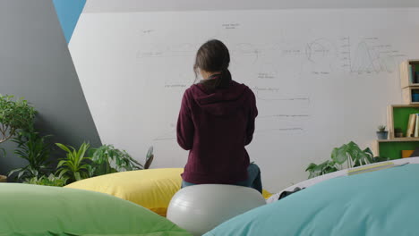 happy caucasian woman student brainstorming ideas enjoying lunch break eating sitting on exercise ball checking smartphone social media messages in modern office workplace