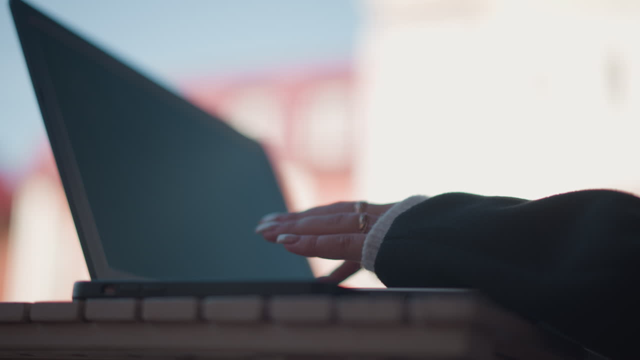 실버 링과 폴리시 된 못으로 장식 된 노트북 키보드에서 타이핑하는 손의 클로즈업, 근처에 스마트폰이있는 나무 테이블에 배치되어 있으며, 흐릿한 배경이 있습니다.