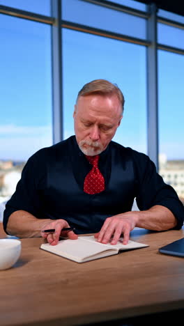 caucasian boss starting his busy working day in the office. adult man opens his laptop, notebook, puts on glasses and touches keyboard on laptop. vertical video.