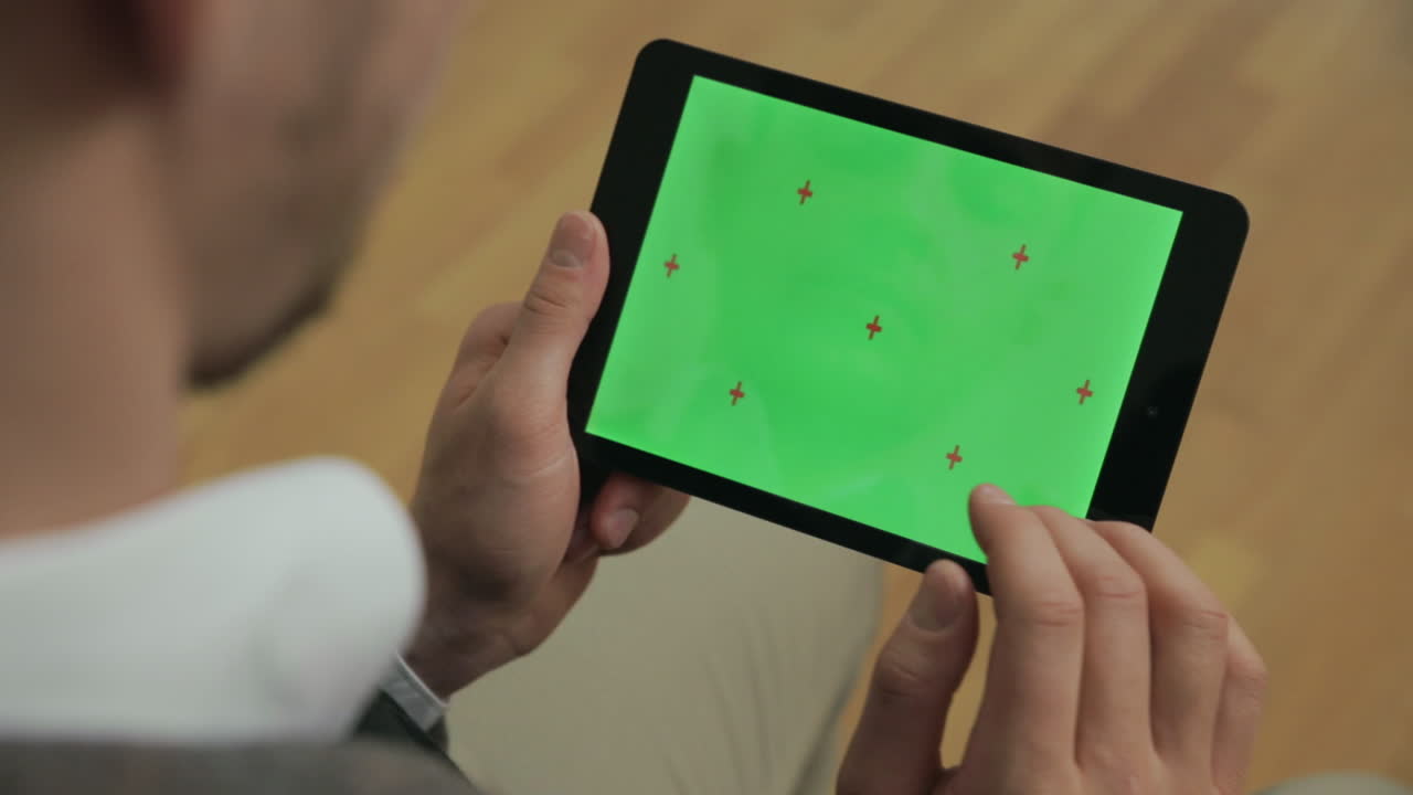 손에 초록색 화면을 가진 태블릿을 들고 있는 남자. 태블릿 화면을 스와이프하는 남자 손