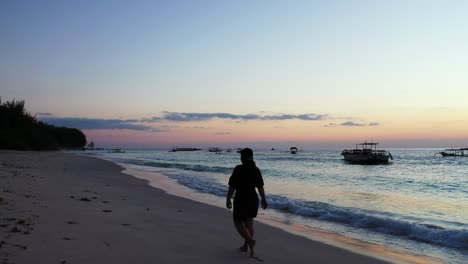 lonely tourist girl walking around exotic beach of seychelles at twilight, watching beautiful sky with blue yellow colors and silhouettes of boats floating