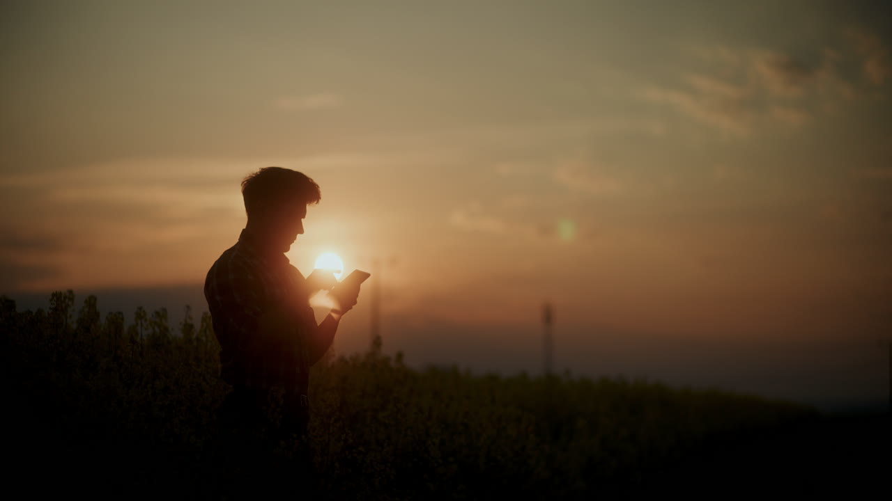 Agronomo che usa un tablet PC in fattoria al tramonto.
