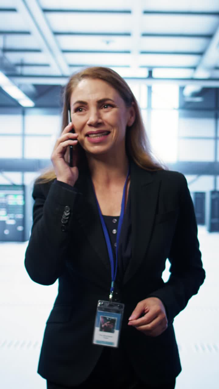 Mujer profesional hablando por teléfono mientras camina en un centro de datos